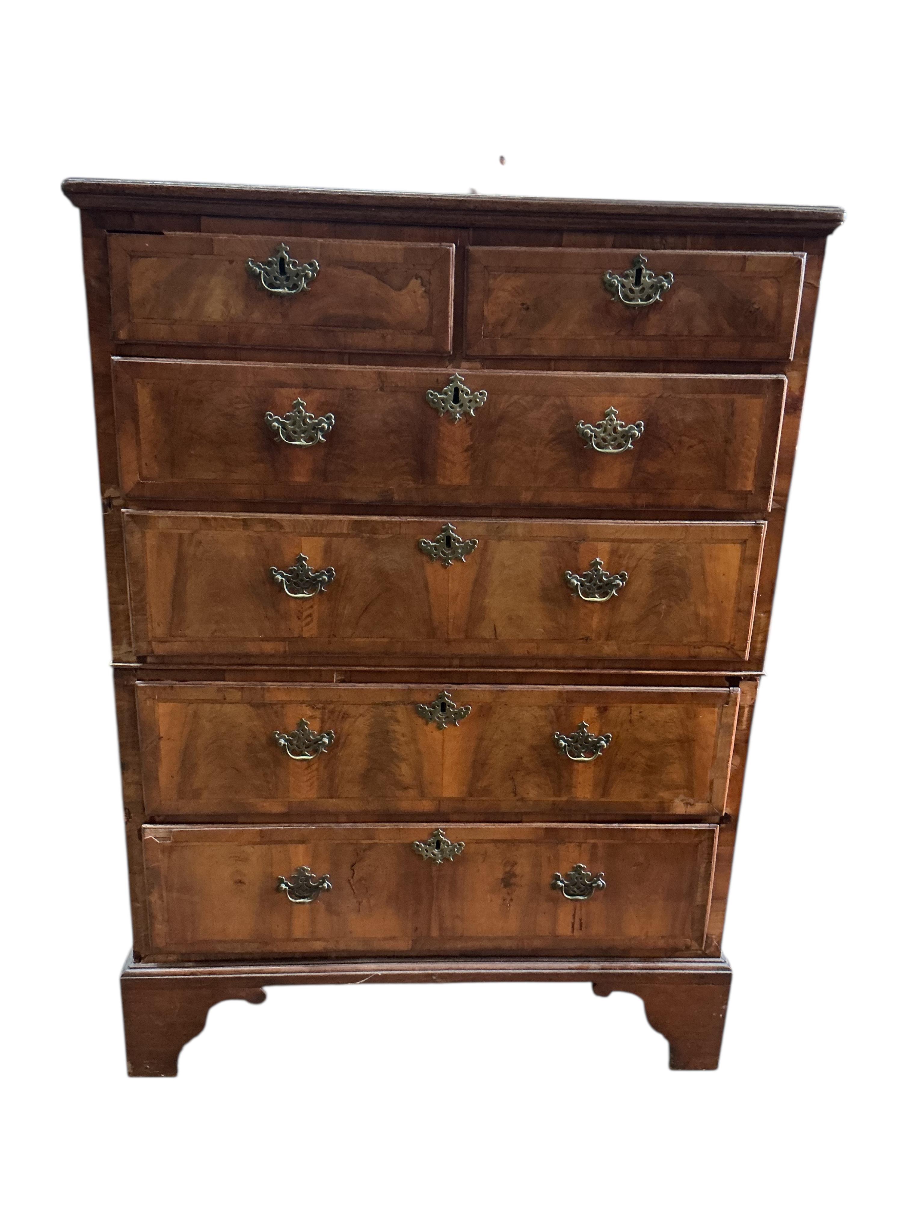 An early 18th century feather banded walnut and pine two section chest of drawers, on later bracket feet and with losses, width 96cm, depth 52cm, height 135cm